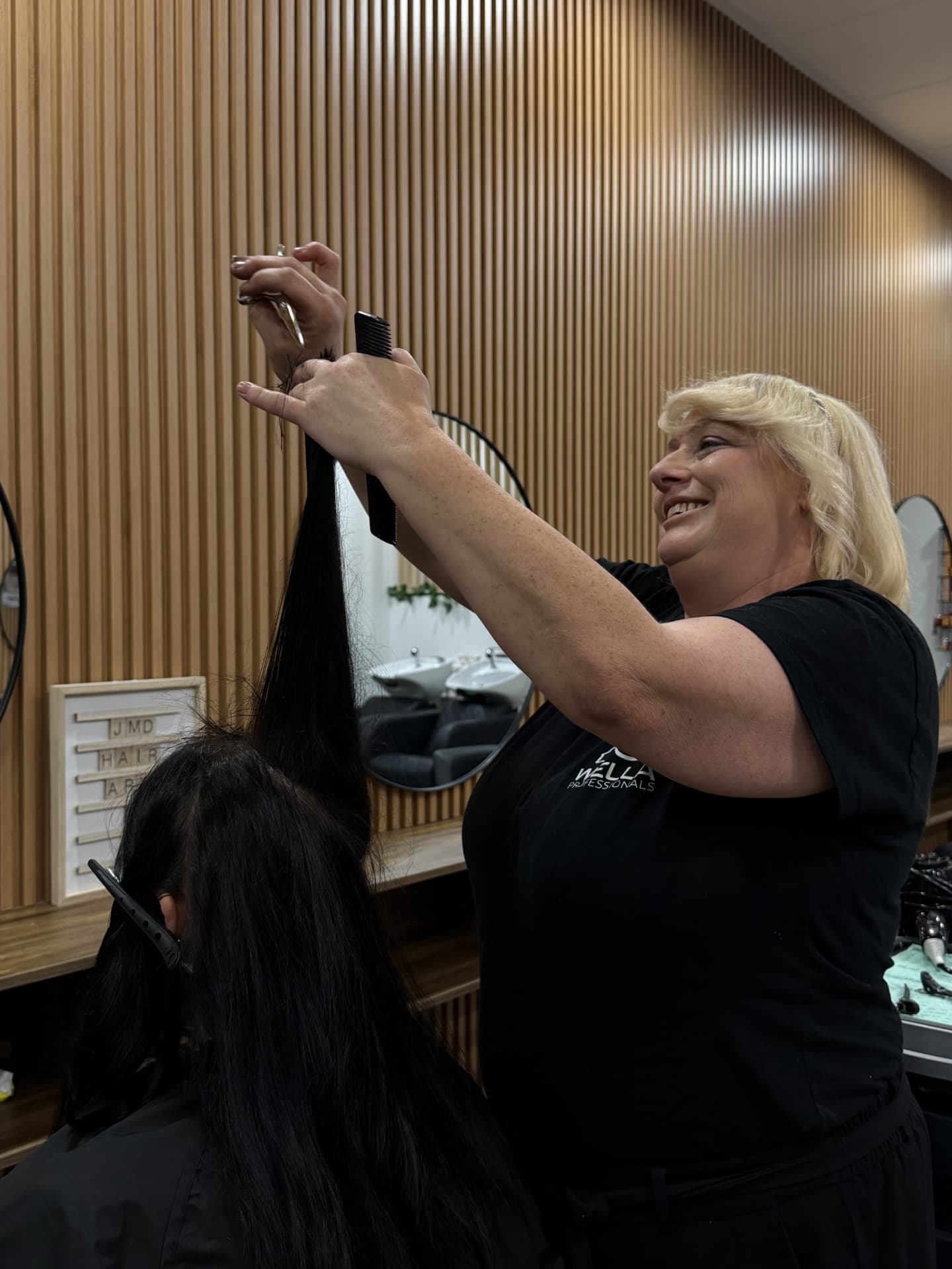 JMD Hair Art stylist trimming long black hair at the salon chair